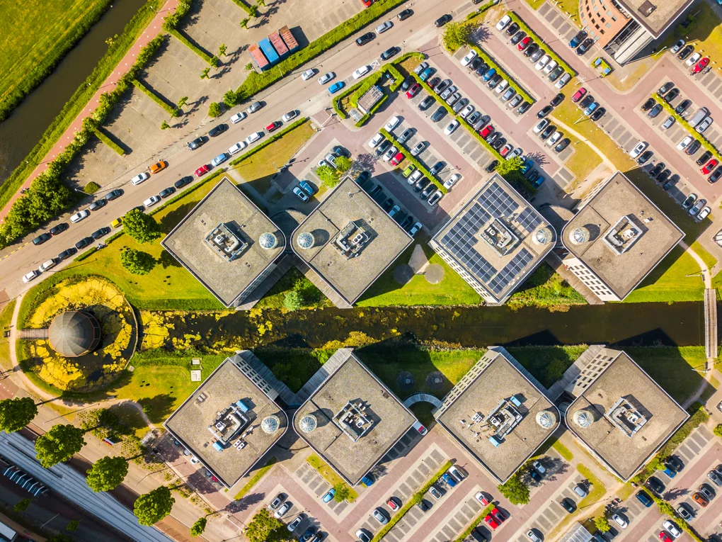 Luchtfoto van kantoorcomplex aan de Rivium Westlaan met zes symmetrisch geplaatste gebouwen en omliggende parkeerplaatsen.